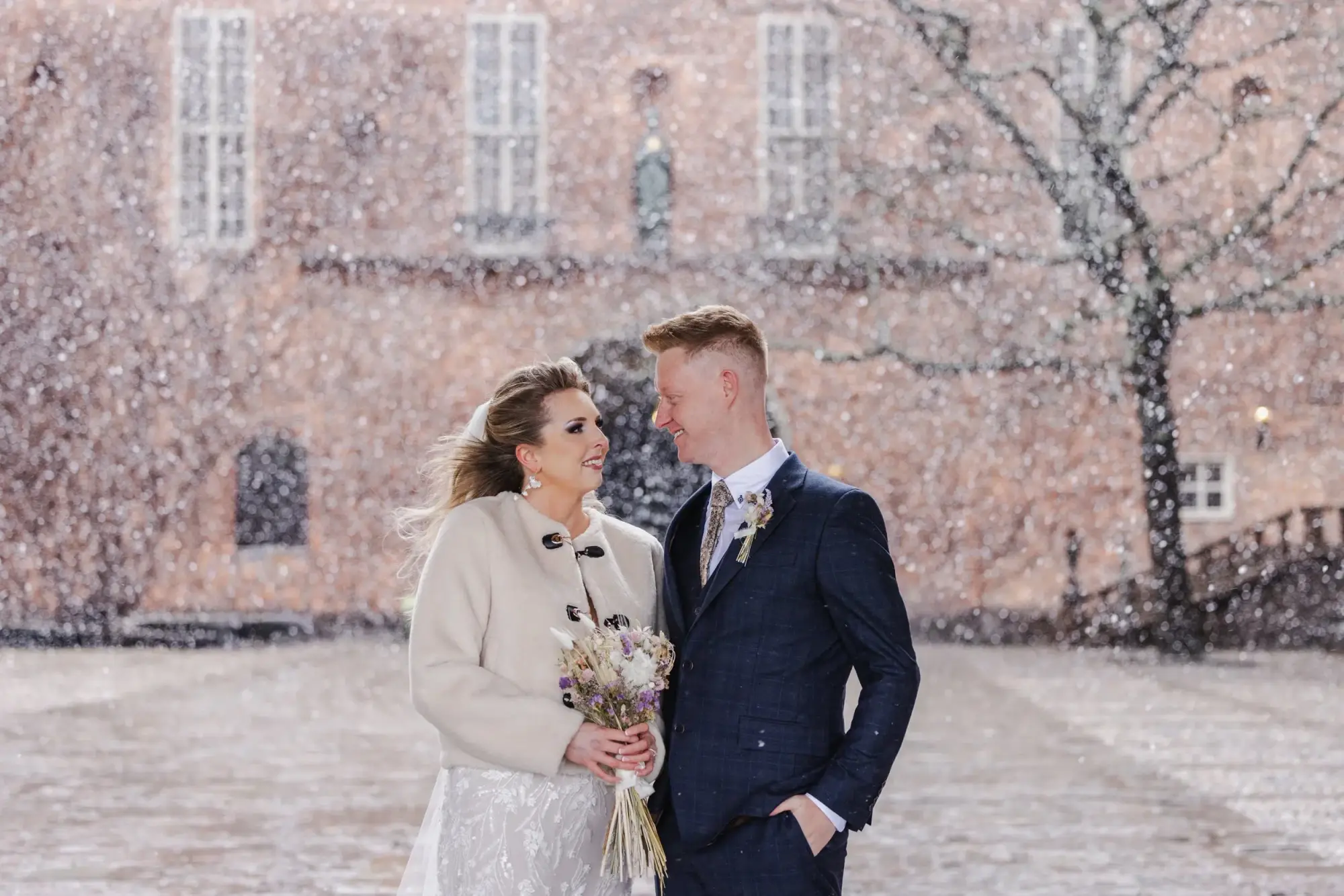 Couple standing together during snowfall at Stockholm City Hall.