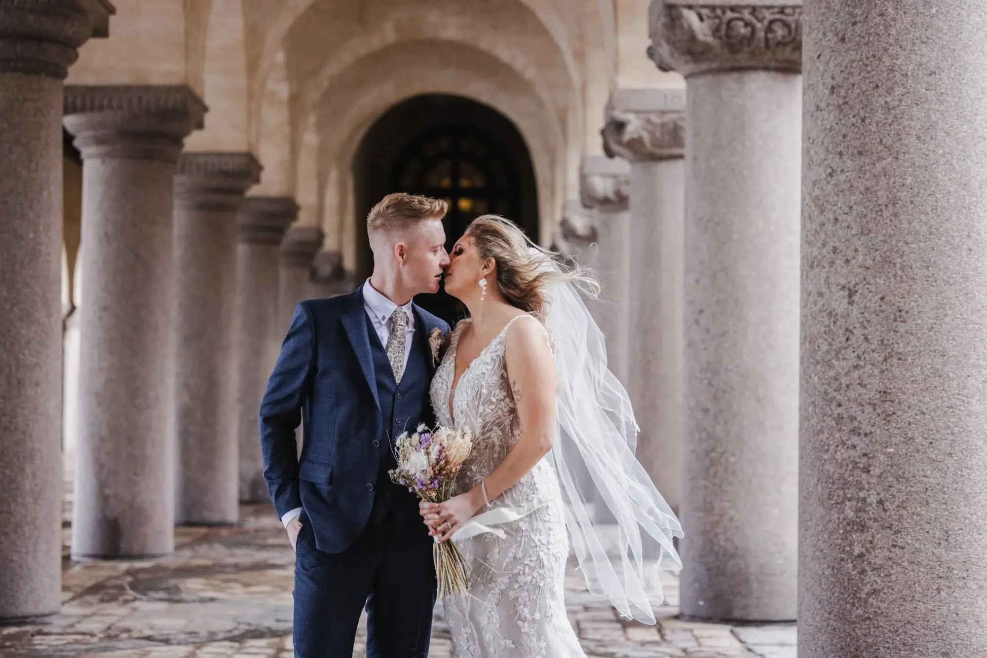 Couple embracing beneath the Stockholm City Hall colonnade.