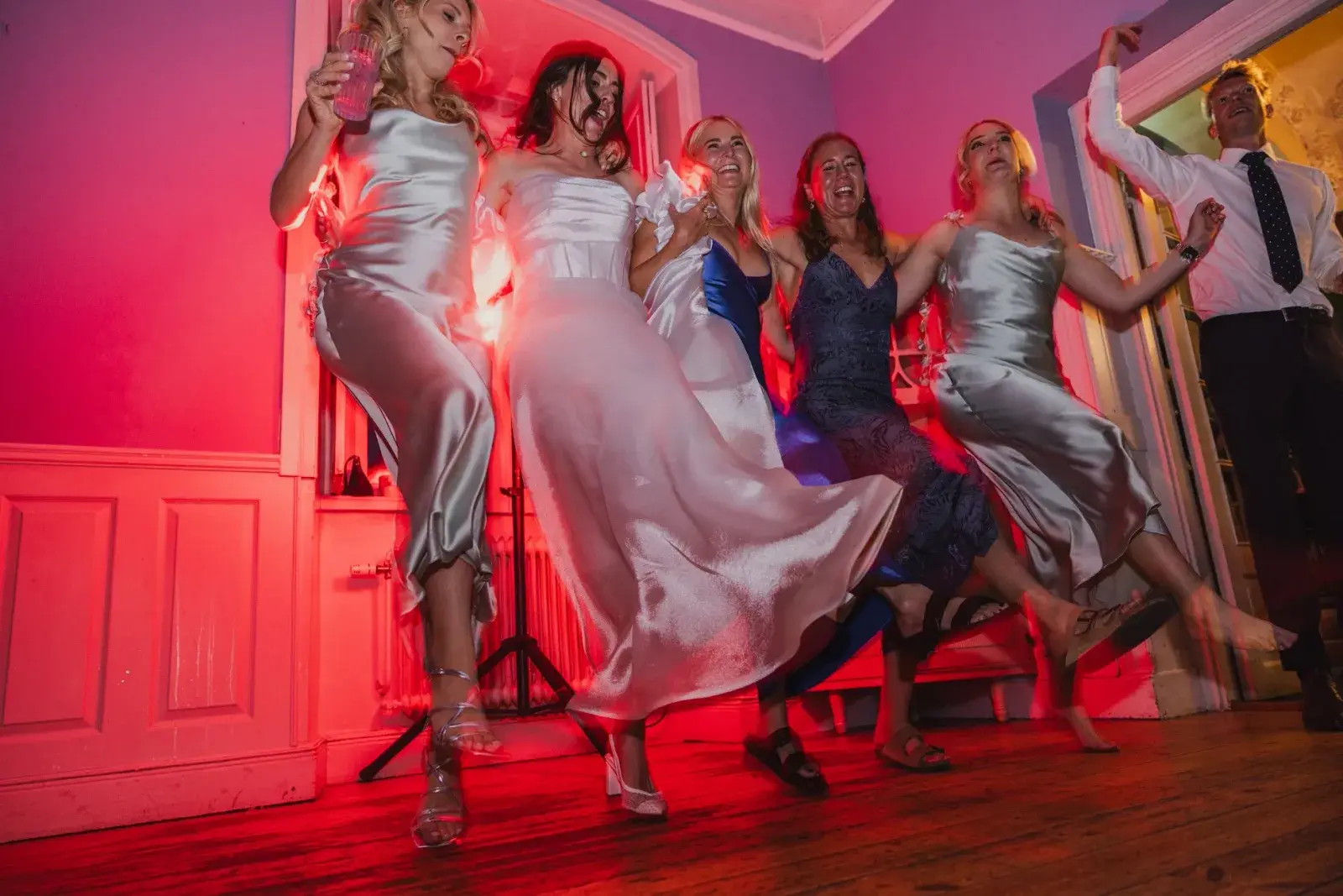 Gabrielle and wedding guests dancing under red light during the wedding reception in Strängnäs.